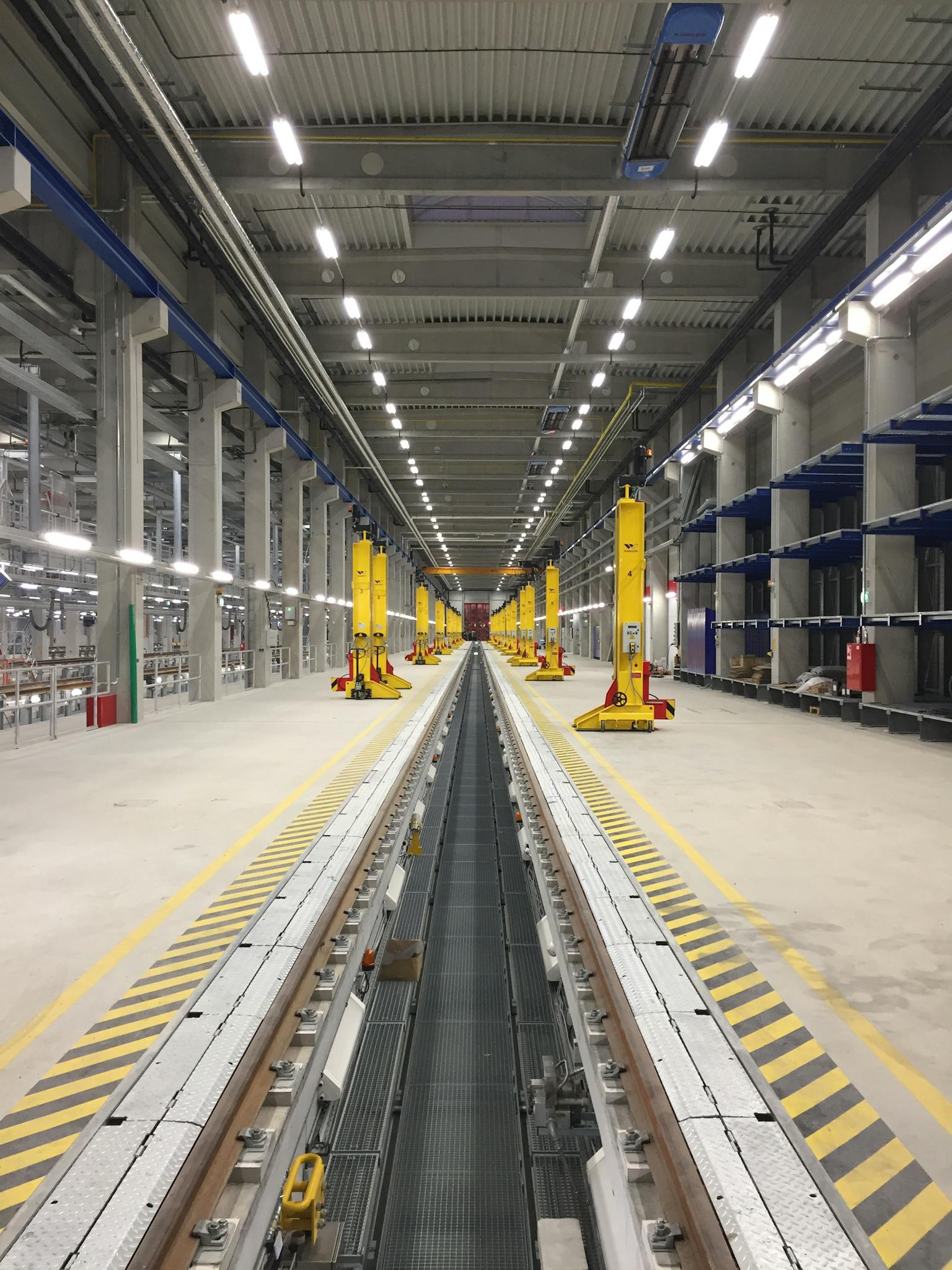 Spacious modern train maintenance facility with parallel tracks and industrial equipment.